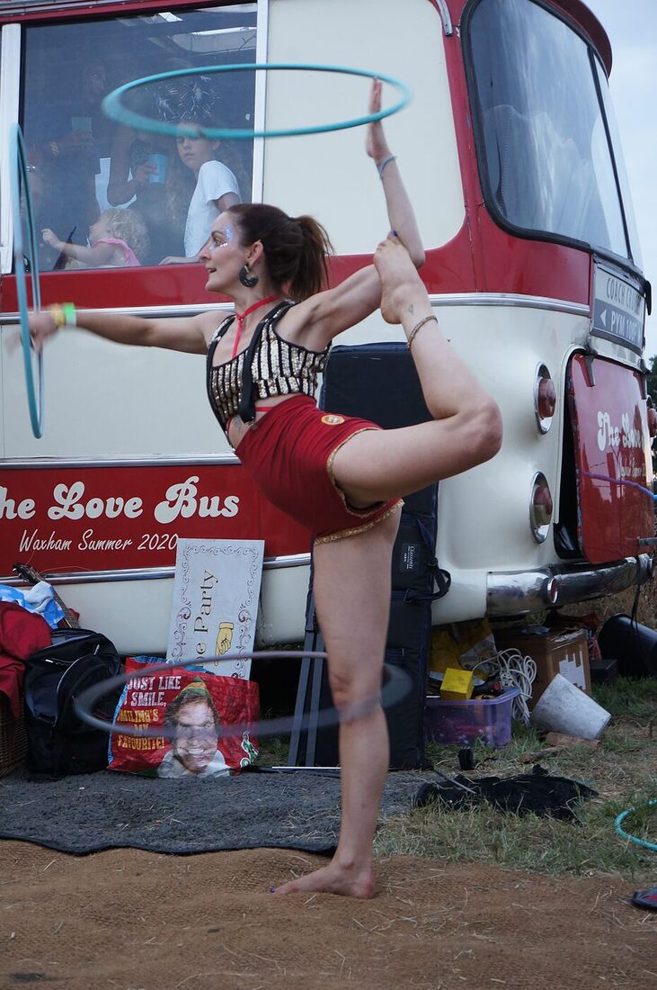 An aerial hoop performer suspended from the front of The Love Bus