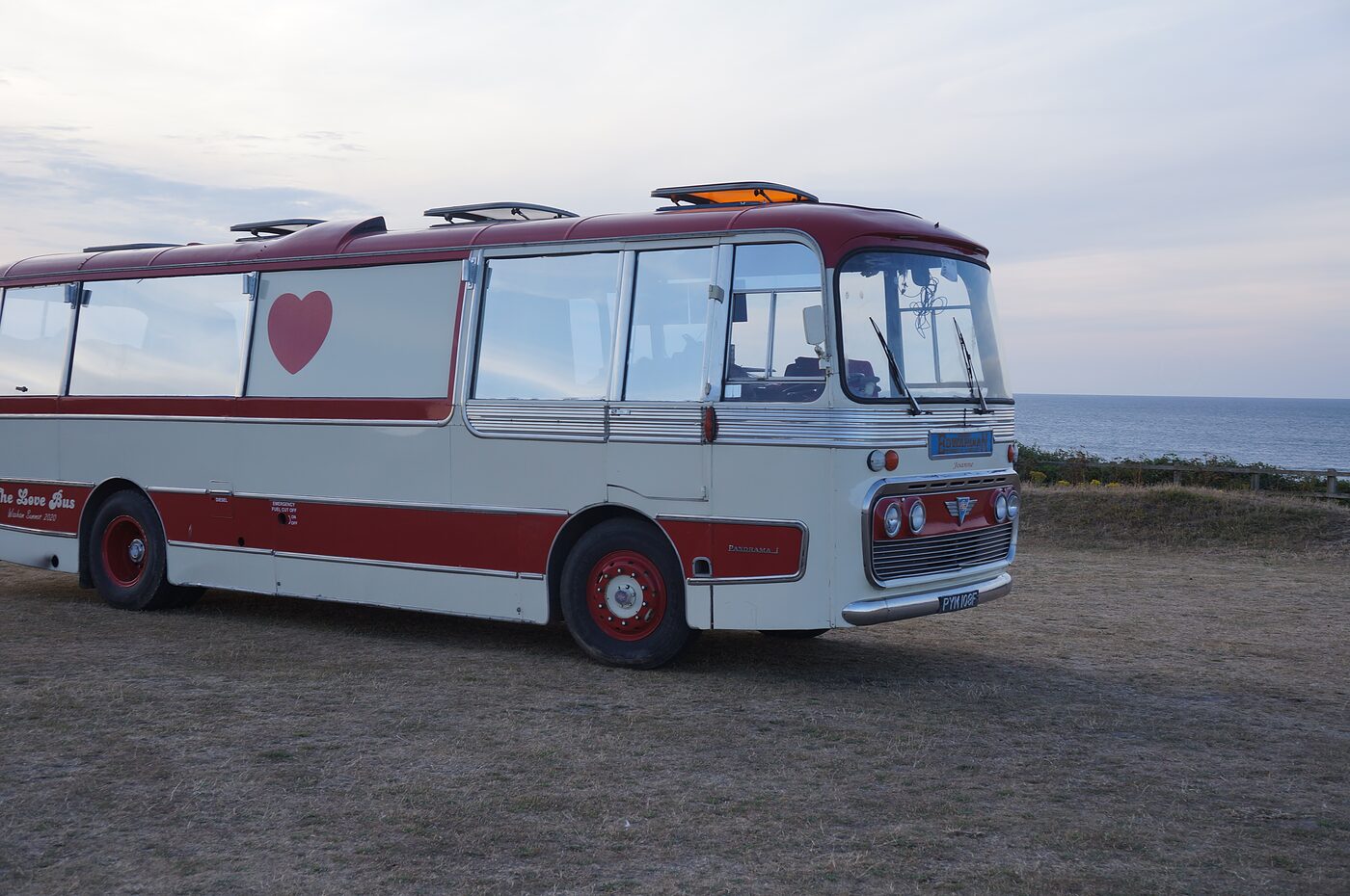 The Love Bus on a clifftop at sunset with the sea behind