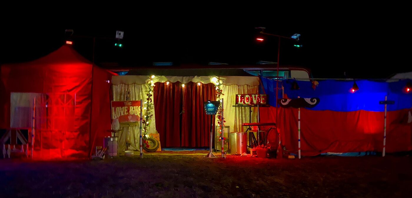 The Love Bus lit in red and blue under its canopy after dark