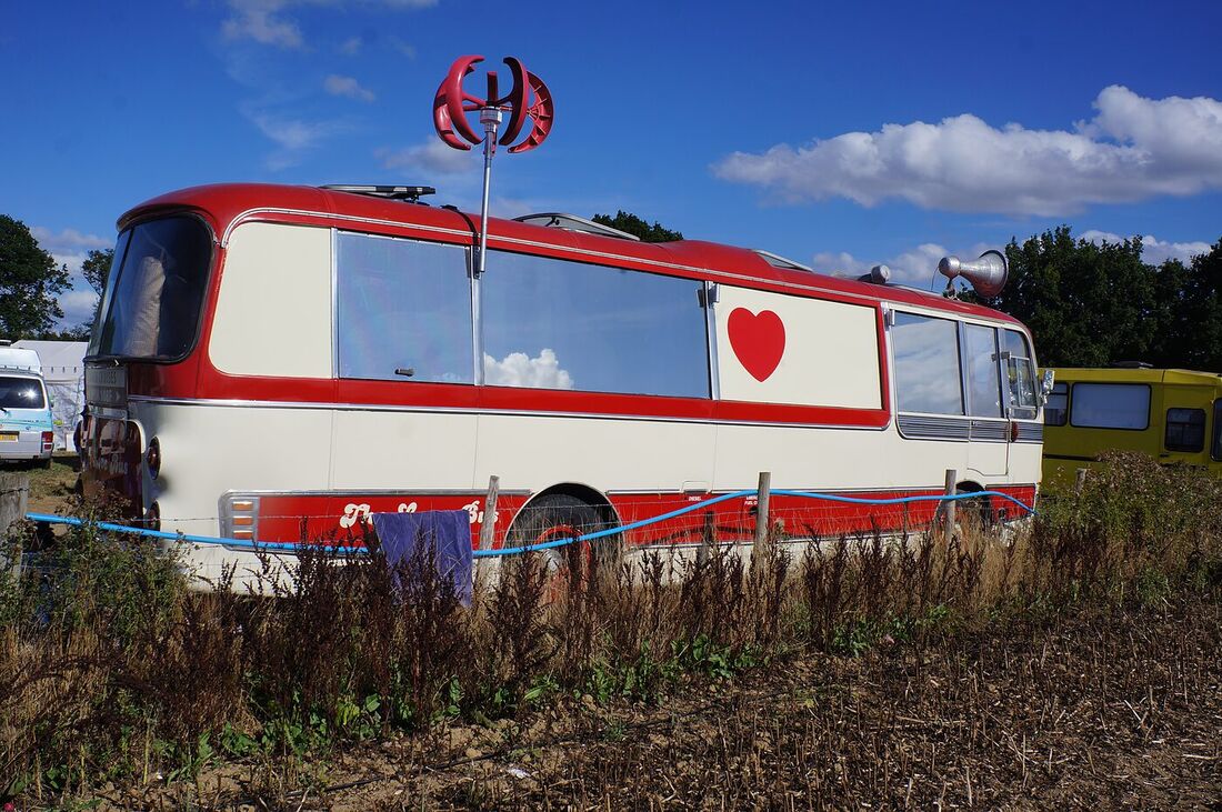 The Love Bus parked in a field under a bright blue sky