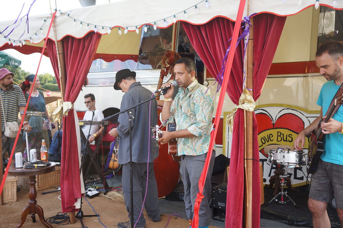 A live band performing beneath the Love Bus sign at a festival