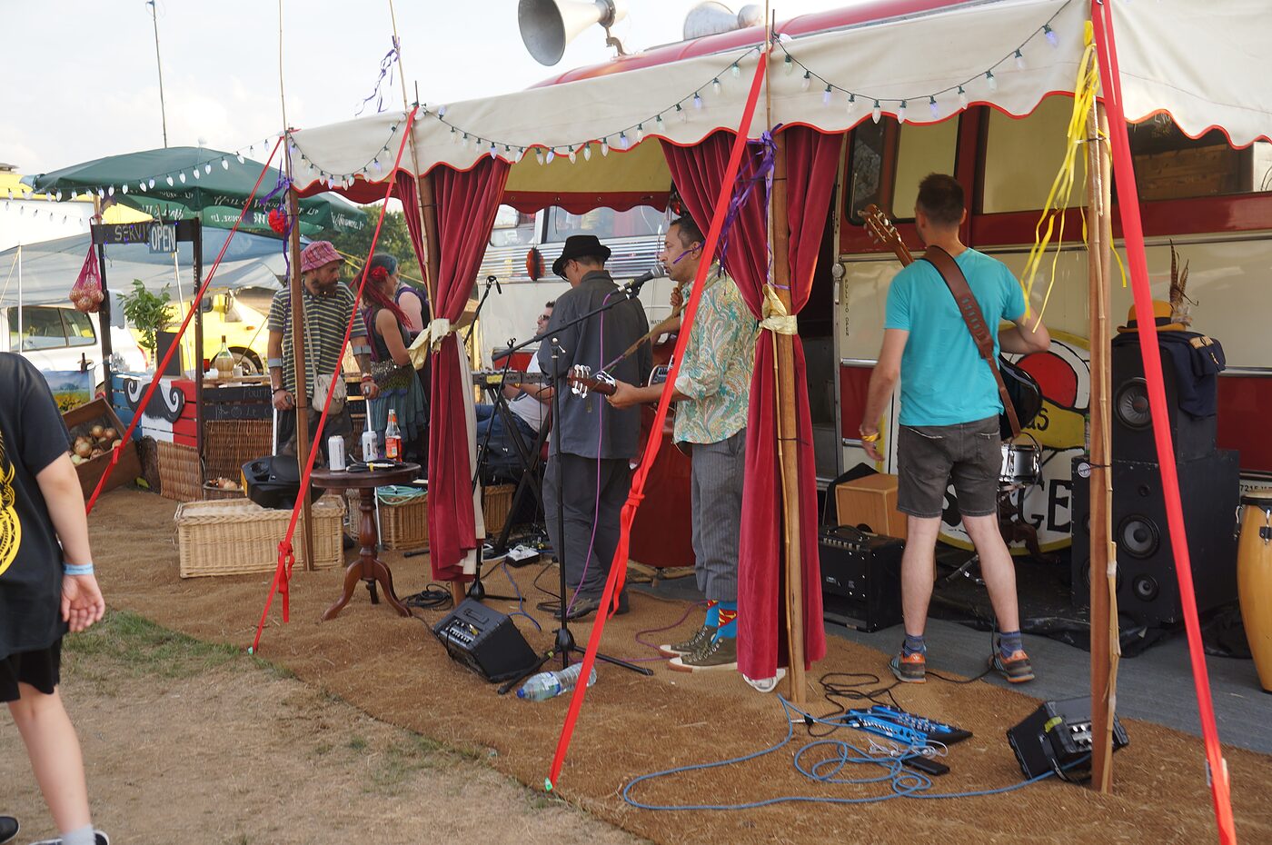 A band playing under The Love Bus awning at a festival