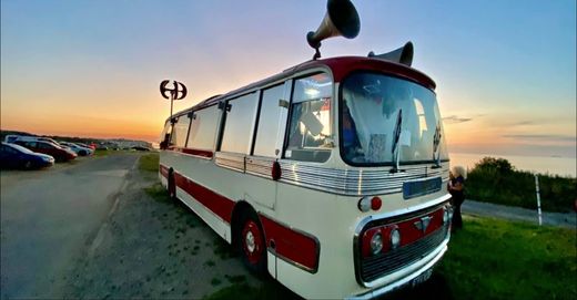 The Love Bus parked on the coast at sunset with its horn speakers and wind turbine
