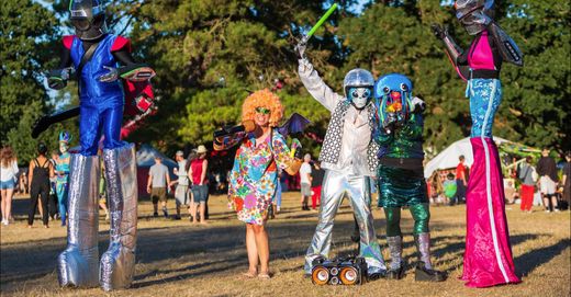 Stilt walkers and costumed performers in silver and bright colours at a festival