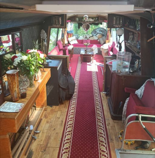 The long aisle of The Love Bus in daylight with fresh flowers and red carpet