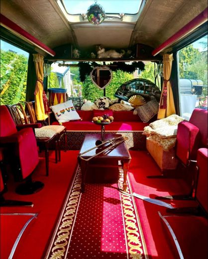 The Love Bus interior in daylight with red seating, a mirror ball and a trombone on the table