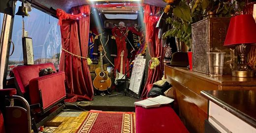 The small stage corner inside The Love Bus with guitars, red velvet curtains and fairy lights