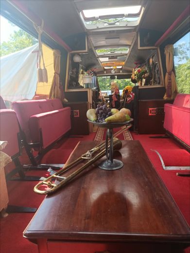 A trombone and a bowl of fruit on the table inside The Love Bus in daylight