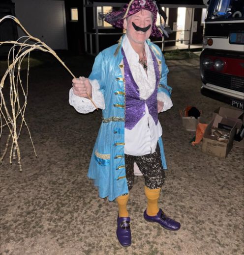 The Great Lorenzo dressed as a pirate captain beside The Love Bus at night