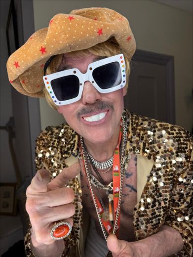 The Great Lorenzo in a gold sequin jacket and white framed sunglasses