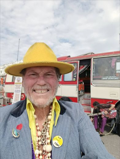 The Great Lorenzo in a yellow hat in front of The Love Bus on the seafront