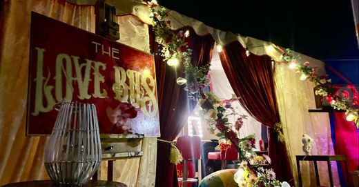 The painted Love Bus sign dressed with flowers and festoon lights at night