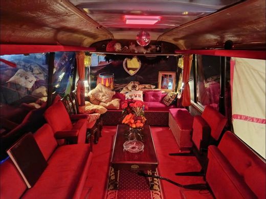 The Love Bus interior at night with red velvet seating, a mirror ball and a bowl of fruit