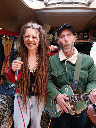 A singer and a guitarist sharing a joke inside The Love Bus