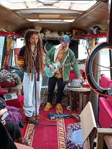 A singer and a guitarist performing inside The Love Bus