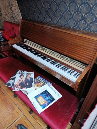 The upright piano on The Love Bus with sheet music resting on the red velvet stool