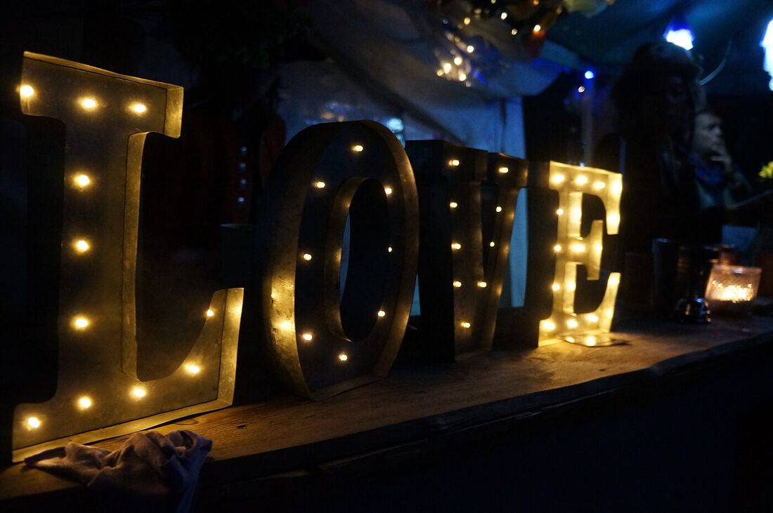 Illuminated LOVE letters beside The Love Bus after dark