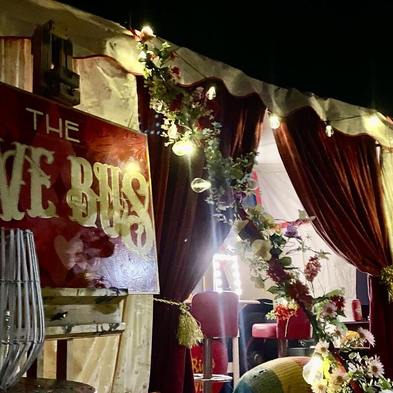 The hand painted Love Bus sign framed by flowers and drapes