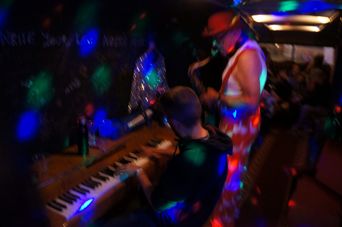 Live piano performance inside The Love Bus under coloured stage lighting